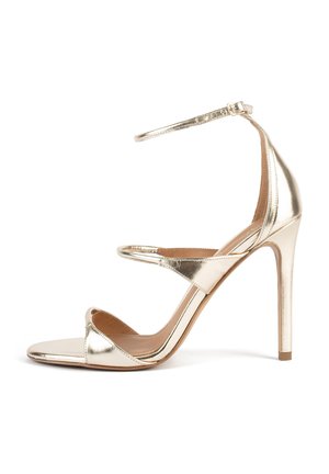 Guldmetalisk hælthøj sandal med tynd ankelrem og spænde og åben tå, der viser en slank stilethæl og minimalistisk design.