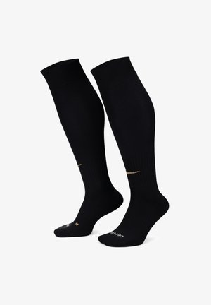 Calze nere fino al ginocchio con texture a coste, dotate di un dettaglio con logo dorato sul lato e aree rinforzate nel tallone e nelle punte.