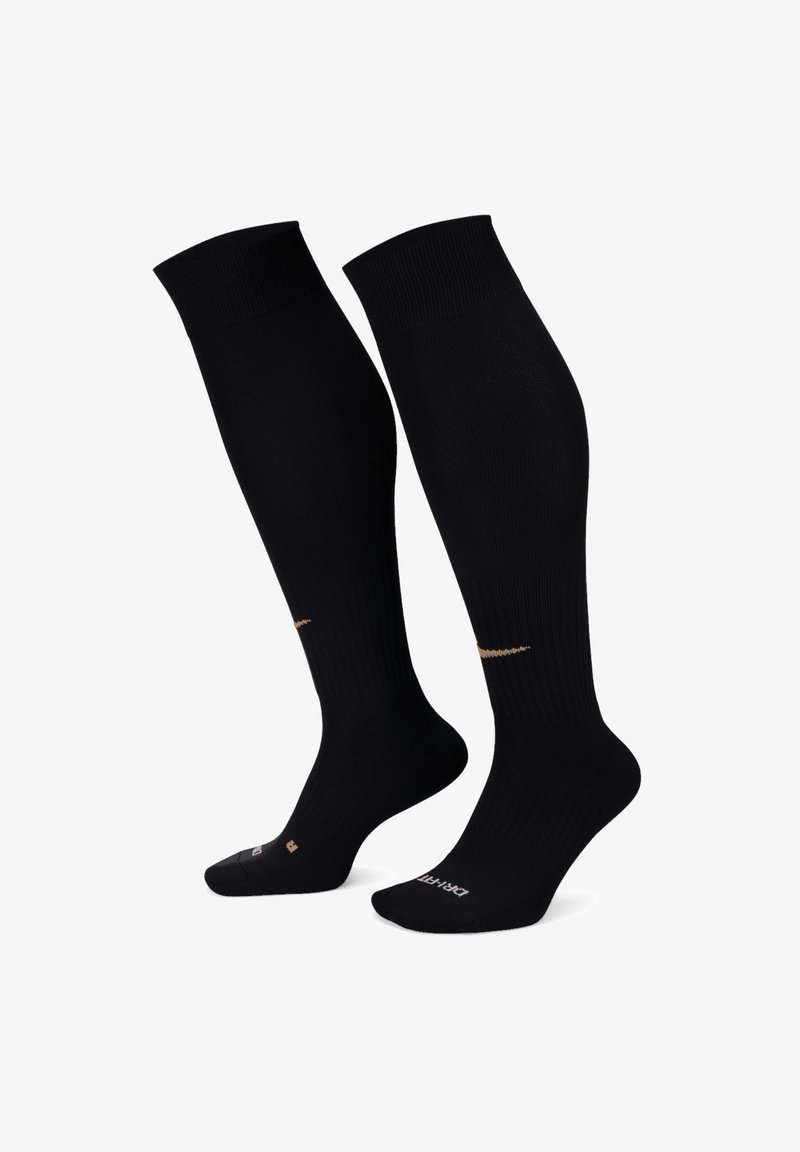 Calze nere fino al ginocchio con texture a coste, dotate di un dettaglio con logo dorato sul lato e aree rinforzate nel tallone e nelle punte.