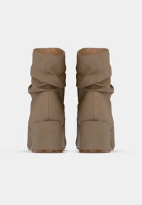 Hnedé pohodlné členkové čižmy z mäkkej látky, s robustným podpätkom, záhybom v oblasti členka a hladkou vnútornou podšívkou.