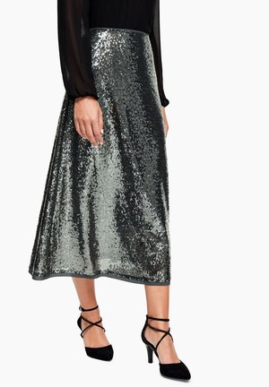 Sølvglitrende midi-nederdel med et flydende design. Stoffet er reflekterende med en glat tekstur; kombineret med sorte sandaler med stropper.