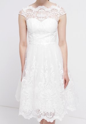 Weißes knieumspielendes Kleid mit aufwendiger floraler Spitzenverzierung, tailliertem Oberteil, transparenten kurzen Ärmeln und einem gewellten Saum.