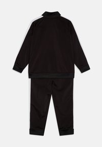 Survêtement de sport noir avec un col, des manches longues, un pantalon assorti et des bandes blanches sur les manches et le pantalon. Texture de tissu lisse.
