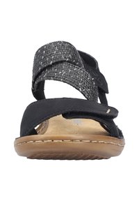Black sandals featuring two textured straps with a woven design, a tan insole, and a flexible outsole for comfort.