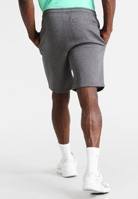 Grå sportshorts med elastisk midja, sidofickor och en bakficka, matchat med vita sneakers och strumpor.