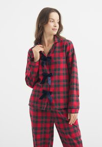 Conjunto de pijama de cuadros rojos con detalles en cinta azul marino, manga larga, camisa abotonada y pantalones a juego de corte relajado.