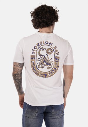 T-shirt bianca a maniche corte con un design grafico multicolore sul retro, raffigurante uno scorpione e elementi testuali.