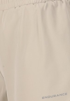 Beige sportsshorts lavet af letvægtsstof med elastisk talje. Har en glat overflade og "ENDURANCE" trykt i grå.