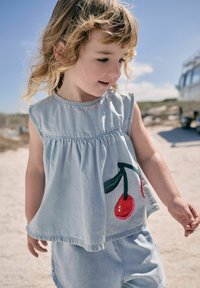 Haut sans manches en denim bleu clair avec taille froncée et broderie de cerises rouges. Assorti à un short. Design doux et décontracté.
