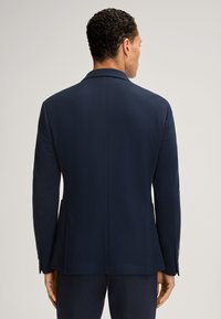Donkerblauwe textuur blazer met visgraatpatroon, enkele split aan de achterkant, inkeping revers en twee zijzakken.