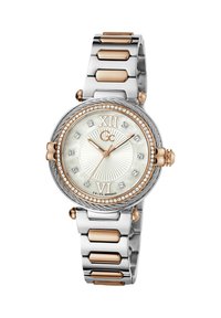 Hõbedane ja roosa kuldne randmekell, mis sisaldab ümmargust küljelt, pärlmutter diali, rooma numbreid, kristallaktsente ning metallist käevõru.