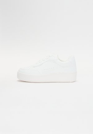 White sneaker with a smooth synthetic upper, rounded toe, low-profile design, and a textured rubber sole featuring vertical grooves.