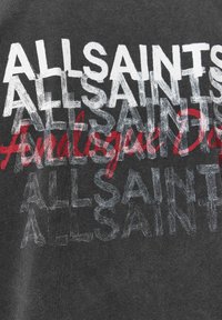 Grå bomulds-T-shirt med gentaget tekst "ALLSAINTS" og "Analog" i rødt. Designet inkluderer varierende opacitet og forskudt placering af teksten.