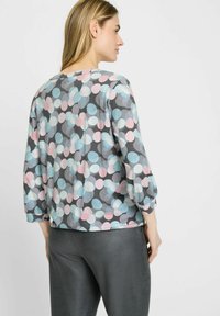 Top met driekwartmouwen van lichtgewicht stof, met een grijze achtergrond en grote, meerkleurige stippen in pastelkleuren.