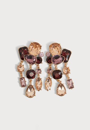 Paire de boucles d'oreilles dorées avec des pierres précieuses facettées roses, violettes et rouge foncé de différentes formes, au design pendante sur un fond clair.