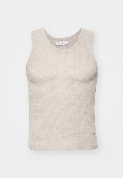 Αμάνικο μπεζ φανελάκι φτιαγμένο από υφασμένο υλικό με υφή. Στρογγυλή λαιμόκοψη και εφαρμοστή γραμμή, με ακατέργαστες άκρες στο στρίφωμα και τις μασχάλες.