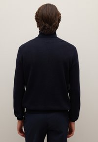 Jersey de punto azul marino con cuello alto, mangas largas y puños y dobladillo acanalados. El material parece suave con una textura lisa.