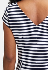 Navy and white striped dress with a V-neckline and short cap sleeves, featuring a smooth, stretchy fabric and a fitted design.