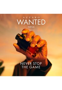Hånd, der holder Azzaro Wanted parfume flaske mod en varm solnedgang baggrund med tekst "Never Stop The Game."