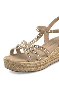Beige wedge sandaal met gekruiste banden versierd met heldere rhinestenen. Heeft een touwgeweven zool en een zachte, gevoerde voetbed.