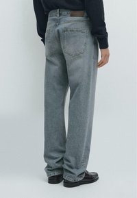 Jasnoszare jeansy o prostych nogawkach z średnim wybarwieniem, pięcioma kieszeniami, subtelnym przeszyciem i fakturowanym wykończeniem. Brązowa skórzana naszywka na pasku.