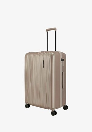 Valise rigide beige avec des rainures verticales, quatre roues pivotantes, poignée télescopique, poignée latérale et serrure à combinaison intégrée.