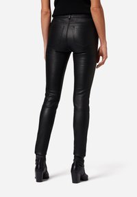 Svarta skinnbyxor i slim fit med en slät yta. Har hög midja, två bakfickor och ankellång design.