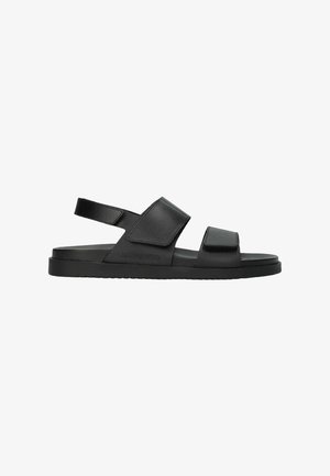 Sandale noire à bout ouvert avec deux larges brides ajustables sur le dessus du pied et une autour du talon, semelle plate, et logo Medphisto sur le côté.