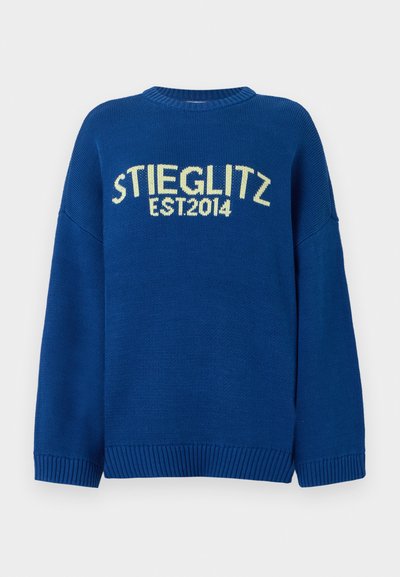 Plavi pleteni pulover s padajućim ramenima, rebrastim manžetama i obrubom. Sadrži kontrastni žuti natpis "STIEGLITZ EST.2014" na prednjoj strani.