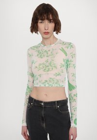 Langermet, kort topp laget av gjennomsiktig stoff med grønne blomster mønstre. Har rund hals og tettsittende design. Brukt med svarte jeans.