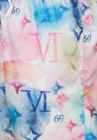 Kleurige stof met een bloemenpatroon in blauwe en roze aquarellen, vergezeld van grote tekst en symbolen. Het materiaal lijkt glad en licht van gewicht.