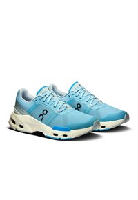 Baskets de sport bleu clair avec un dessus en maille, un col rembourré et une semelle à amorti prononcé ; présentent un logo et des accents contrastants.