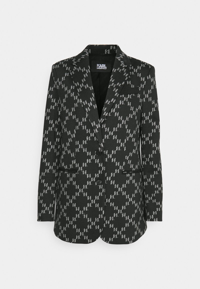 Blazer a righe in bianco e nero con rever a punta, due tasche frontali e due bottoni neri. Il tessuto ha una finitura testurizzata.