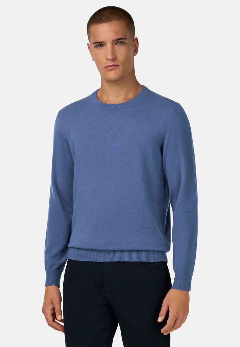 Šviesiai mėlynas megztinis su apskritu iškirpimu, ilgomis rankovėmis ir gumuotais rankogaliais. Lygus audinys, įliemenuotas juosmenyje.