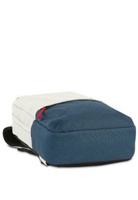 Mochila con una parte superior gris claro y un fondo azul oscuro, con una superficie texturada y un tirador de cremallera rojo, acentuada con correas negras.