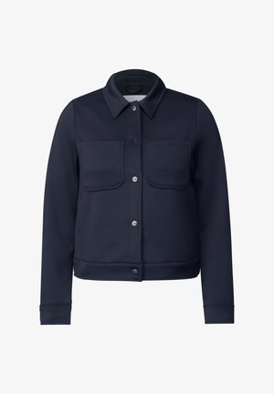 Tummansininen takki, joka on valmistettu pehmeästä kankaasta. Takissa on napitettu etuosa, kaksi rintataskua ja ribbireunus sekä hihansuut, jotka luovat istuvan ilmeen.