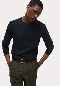 Námořnický svetr s kulatým výstřihem a dlouhými rukávy, s žebrovanými manžetami a lemem, spárovaný s olivově zelenými cargo kalhotami a hnědým pásem.