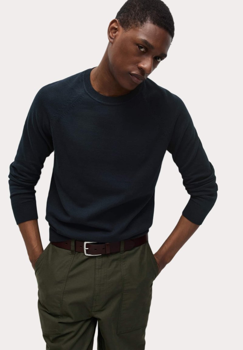 Námořnický svetr s kulatým výstřihem a dlouhými rukávy, s žebrovanými manžetami a lemem, spárovaný s olivově zelenými cargo kalhotami a hnědým pásem.