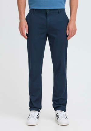 Navy chinos med slim fit, tillverkade av ett mjukt bomullstyg, med knappstängning fram och sidofickor, i kombination med vita sneakers.