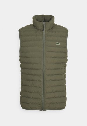 Veste sans manches matelassée vert olive avec fermeture éclair à l'avant et petit logo crocodile brodé sur la poitrine gauche.