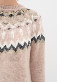 Pletena majica v nežno roza barvi z okroglo izrezom, ki ima okoli yoke vzorec fair isle v črni, beli in bež barvi.