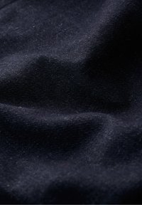 Tissu bleu marine foncé avec une surface texturée, montrant de fins tissages et de subtiles variations de teinte. Apparence douce avec un léger éclat.