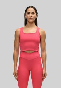 Rosa atletisk crop-top med fyrkantig halsringning, kombinerad med matchande högmidjade leggings med en vinkelcutout-detalj. Slät textur.