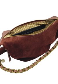 Sac à main en suédine marron avec une bandoulière en chaîne dorée, doté d'un intérieur jaune à motif floral et d'une poche zippée à l'intérieur.