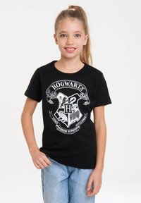Black cotton T-shirt featuring a white Hogwarts logo graphic with a shield design and text "HOGWARTS" above. Short sleeves, classic fit.