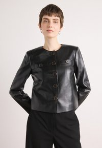 Black leather jacket with a round neckline, long sleeves, six button closures, and two flap pockets. Smooth texture and tailored fit.