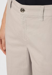 Pantalons en coton gris clair avec une texture lisse, dotés d'un bouton en métal argenté à la taille et d'un design classique à cinq poches.