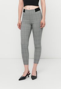 Sive karirane legice z oprijetim krojem, ki imajo visok pas s črnimi poudarki. Nosi se z črnimi slingback petami.