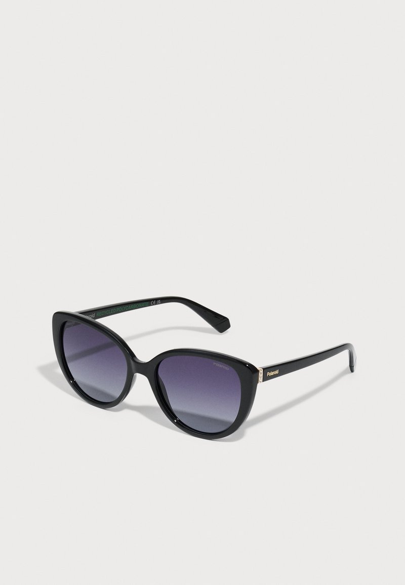 Ochelari de soare negri cu o formă supradimensionată în stil cat-eye, lentile gri gradient și un finisaj lucios. Include accente de hardware aurii pe brațe.