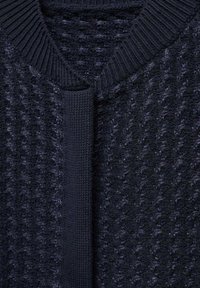 Pull en maille bleu marine foncé avec motif texturé et détail d'encolure en V côtelée.